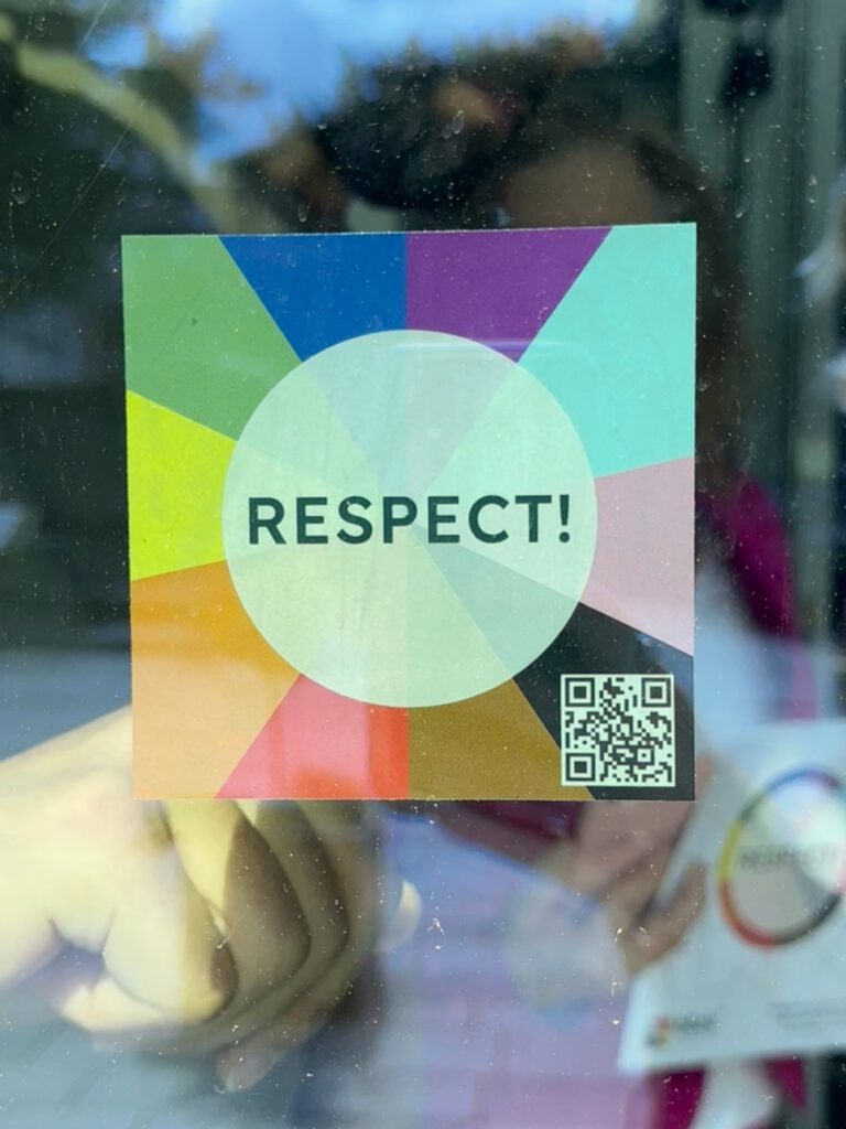 Eine Person bringt einen RESPECT!-Aufkleber an einer Glastür an