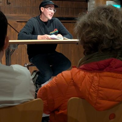 Autor Brix Schaumburg sitzt auf der Bühne bei seiner Lesung.