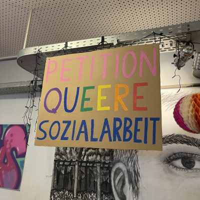 Pappschild mit der bunten Aufschrift "Petition Queere Sozialarbeit"